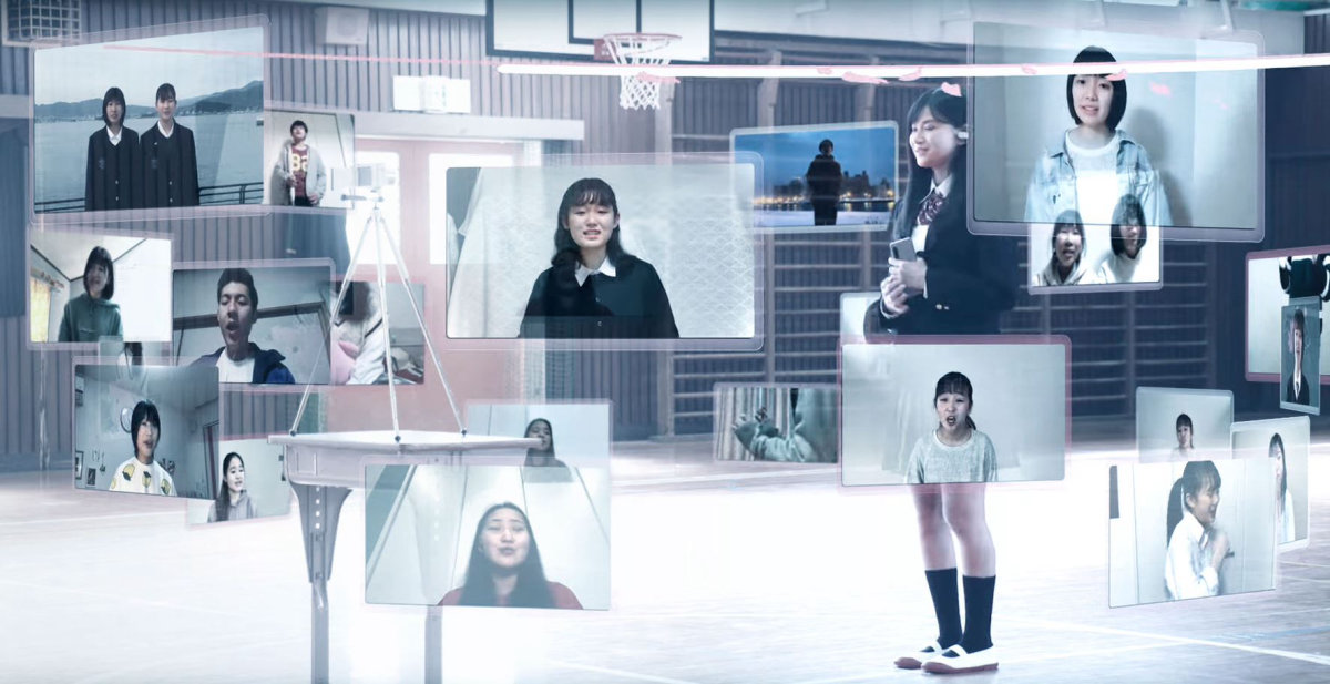 Composite image of school children on separate video screens singing 