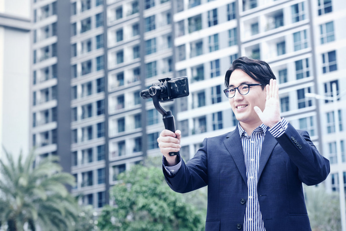 A man recording a video of himself on a cellphone outdoors